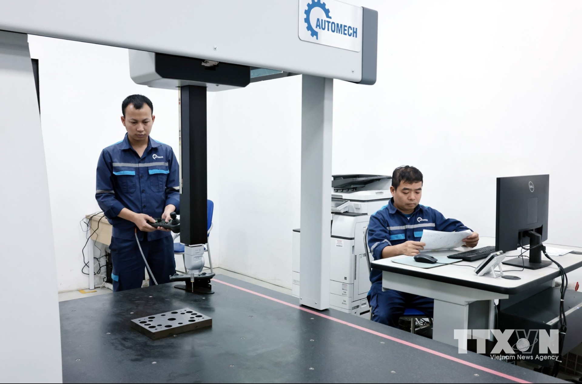 Các kỹ thuật viên điều khiển máy kiểm tra chất lượng sản phẩm của Automech. (Ảnh: Trần Việt/TTXVN)